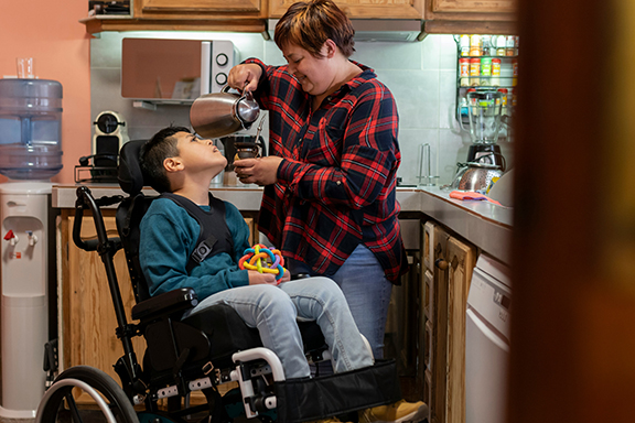 Medically Fragile Children group image - boy in wheelchair with caregiver